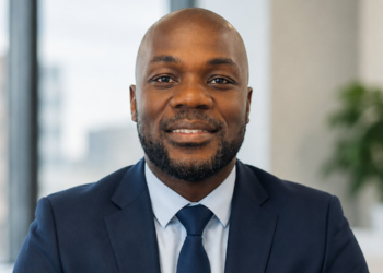 Portrait of a smiling African American man in a navy suit and tie in an office setting.