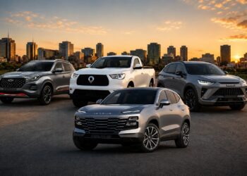 Five modern vehicles (two SUVs, a pickup, and two more SUVs) parked in a row on a paved lot with a city skyline at sunset in the background.