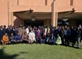 WhatsApp Image 2026-06-23 at 102305 AM - The Brief | Namibia's Leading Business & Financial News Large diverse group of adults posing for a group photo on a green lawn in front of a peach-colored building entrance.