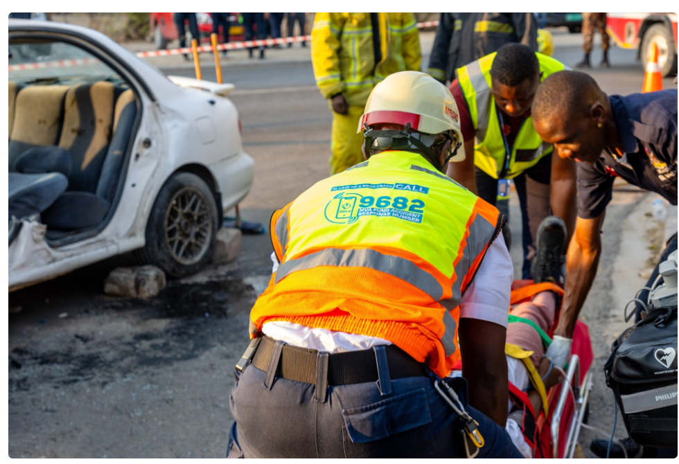 MVA Fund - The Brief | Namibia's Leading Business & Financial News Emergency responders in high-visibility vests assist a person on a stretcher at the scene of a car crash nearby another damaged white car and debris on the road.