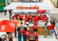 Busy Vida e Caffè kiosk in a mall, staff in red uniforms serve customers at the counter with coffee machines and pastries on display.