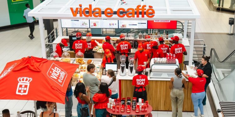 Busy Vida e Caffè kiosk in a mall, staff in red uniforms serve customers at the counter with coffee machines and pastries on display.