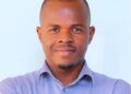 Mr Michael Neema - The Brief | Namibia's Leading Business & Financial News Portrait of a man with short hair and a goatee, smiling in a light blue button-down shirt against a pale blue background.