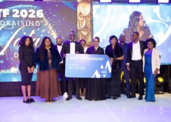 Group of ten formally dressed people on a stage holding a large blue sponsorship check that reads 'OATF Sponsorship' for N$350,000, with a bright event backdrop on screens behind them.