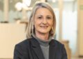 Lorelle Viljoen - The Brief | Namibia's Leading Business & Financial News Portrait of a smiling blonde woman in a gray turtleneck and dark blazer, in an office setting behind her.
