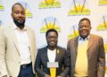 Three men in business attire posing for a photo at an Electricity Control Board event; center man holds a trophy.