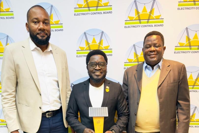 Three men in business attire posing for a photo at an Electricity Control Board event; center man holds a trophy.