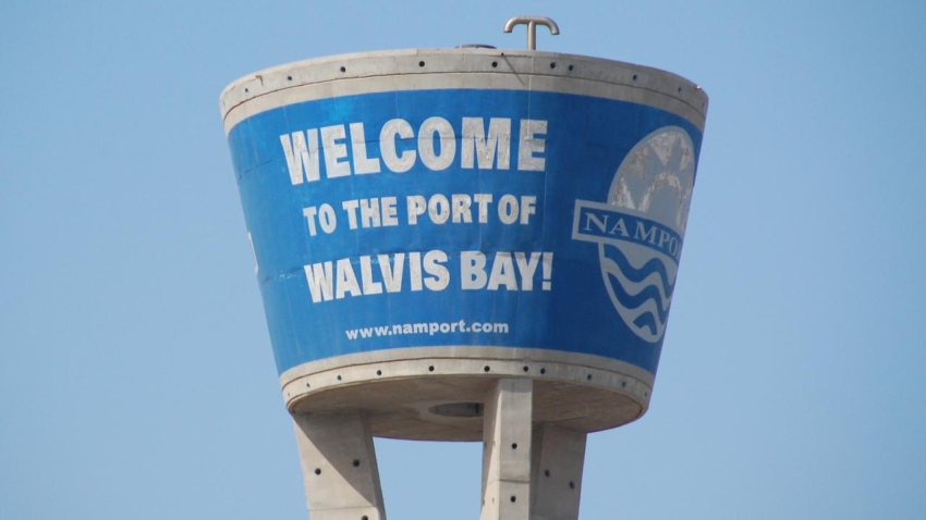 Namport - The Brief | Namibia's Leading Business & Financial News Blue water-tole sign on a cylindrical water tower that reads 'Welcome to the Port of Walvis Bay!' against a clear sky with a port logo on the right side.