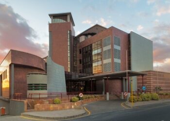 BANK OF NAMIBIA - The Brief | Namibia's Leading Business & Financial News Modern multi-story building with red-brick and glass facade, curved entrance, and driveway at sunset.