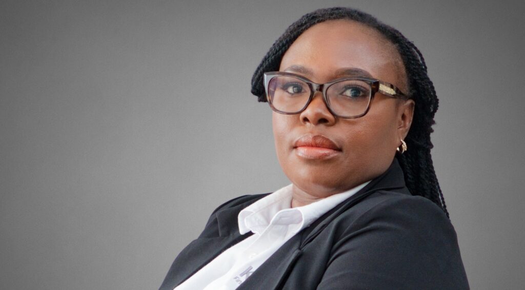 047-KULENI - The Brief | Namibia's Leading Business & Financial News Professional woman in a black blazer and white shirt, wearing glasses, looking to the right against a gray gradient background