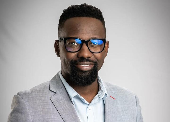 Shita Shimwe - The Brief | Namibia's Leading Business & Financial News Professional headshot of a smiling Black man wearing glasses and a light gray blazer against a neutral backdrop.