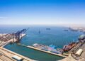 WALVIS BAY PORT - The Brief | Namibia's Leading Business & Financial News Industrial port with container cranes and a white passenger ship docked at a quay, blue sea and clear sky.