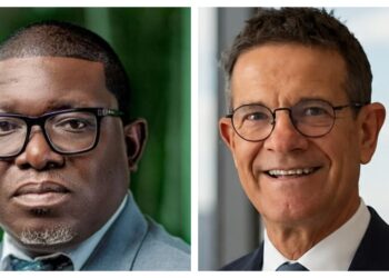 Side-by-side headshots of two men in suits wearing glasses: left, younger man with dark skin tone and rectangular frames; right, older man with lighter skin and round frames smiling.
