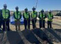 WhatsApp Image 2026-07-16 at 33528 PM - The Brief | Namibia's Leading Business & Financial News Six construction workers wearing hard hats and neon vests stand with shovels in front of a dirt mound at a groundbreaking event on an arid construction site.
