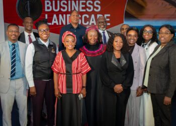 Group of diverse professionals posing for a photo at a business leadership event, with a red banner behind them reading 'BUSINESS LEADERSHIP'.