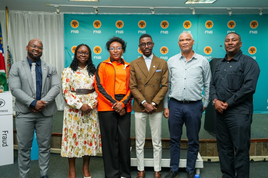 WhatsApp Image 2026-07-27 at 25914 PM - The Brief | Namibia's Leading Business & Financial News Group of six professionals posing for a photo at a corporate event, standing in front of a blue FNB backdrop.