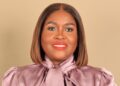 Dr Etuna Simon - The Brief | Namibia's Leading Business & Financial News Smiling woman with a shoulder-length brown bob, wearing a pink satin blouse against a beige background.