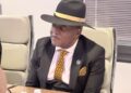 WhatsApp Image 2026-07-30 at 43553 PM - The Brief | Namibia's Leading Business & Financial News Man in a black suit with a yellow polka-dot tie and fedora, seated at a conference table and looking to the side.