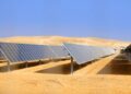 Solar panels installed in a desert landscape, arranged in rows under a clear blue sky for photovoltaic energy generation.
