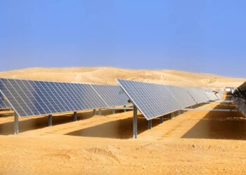 Solar panels installed in a desert landscape, arranged in rows under a clear blue sky for photovoltaic energy generation.