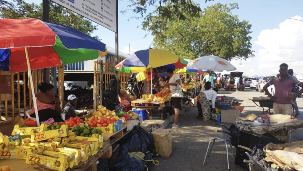 WhatsApp Image 2026-07-31 at 112302 AM - The Brief | Namibia's Leading Business & Financial News Outdoor street market with colorful umbrellas and fruit stalls along a sunny sidewalk.