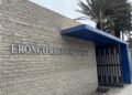 Erongo Regional Council sign on a beige brick wall with a blue canopy over a gated entrance along a sidewalk.