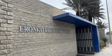 Erongo Regional Council sign on a beige brick wall with a blue canopy over a gated entrance along a sidewalk.