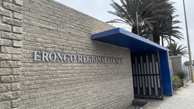 Erongo Regional Council sign on a beige brick wall with a blue canopy over a gated entrance along a sidewalk.