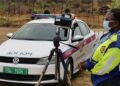 traffic officer - The Brief | Namibia's Leading Business & Financial News Female police officer in a neon jacket and mask stands beside a white patrol car with a camera on a tripod for speed enforcement.