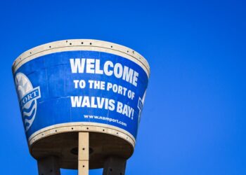 WALVIS BAY 1 - The Brief | Namibia's Leading Business & Financial News Blue water-tank sign reads 'WELCOME TO THE PORT OF WALVIS BAY' against a clear blue sky, with part of the port logo visible on the left.