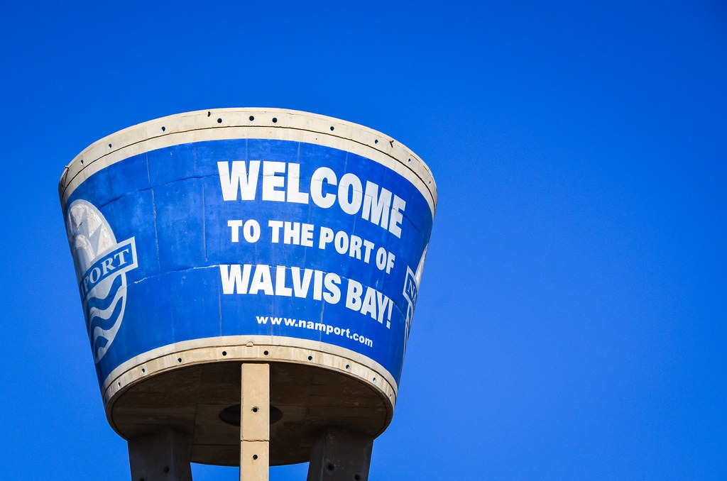WALVIS BAY 1 - The Brief | Namibia's Leading Business & Financial News Blue water-tank sign reads 'WELCOME TO THE PORT OF WALVIS BAY' against a clear blue sky, with part of the port logo visible on the left.