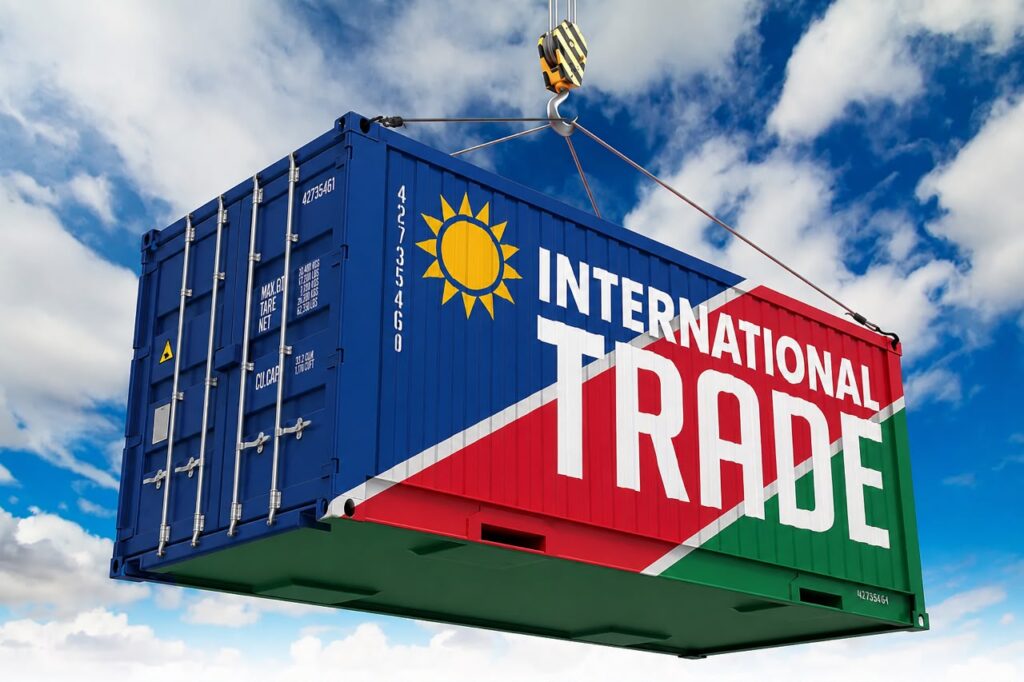 INTERNATIONAL TRADE1 - The Brief | Namibia's Leading Business & Financial News Blue shipping container being lifted by a crane, painted with a bold 'INTERNATIONAL TRADE' banner and sun emblem against a blue sky.