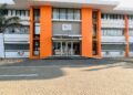 CPBN - The Brief | Namibia's Leading Business & Financial News Front entrance of a modern white building with bright orange vertical columns, glass doors, and a small CPBN sign above the doorway.