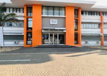 Front entrance of a modern white building with bright orange vertical columns, glass doors, and a small CPBN sign above the doorway.