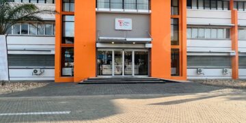 Front entrance of a modern white building with bright orange vertical columns, glass doors, and a small CPBN sign above the doorway.