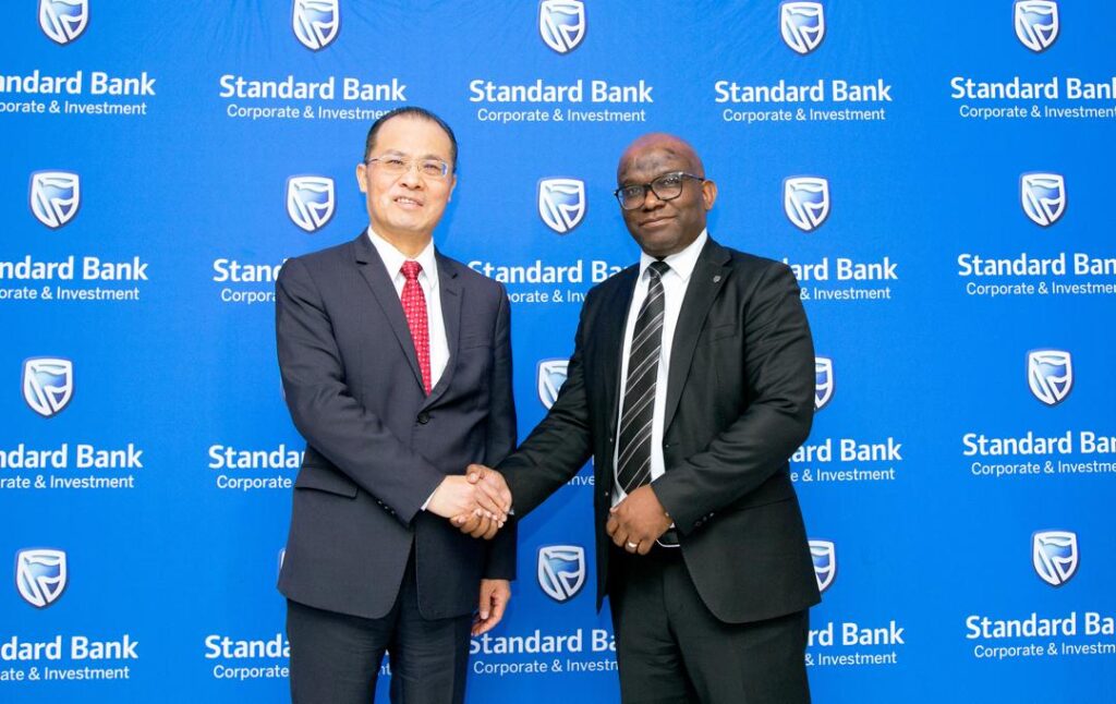 WhatsApp Image 2026-08-10 at 124610 PM - The Brief | Namibia's Leading Business & Financial News Two businessmen in suits shake hands in front of a blue Standard Bank backdrop at a corporate event.
