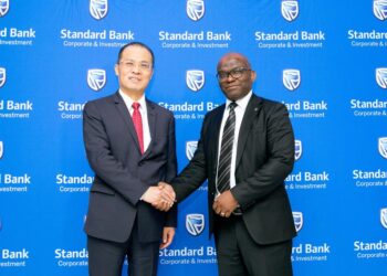 WhatsApp Image 2026-08-10 at 124610 PM - The Brief | Namibia's Leading Business & Financial News Two businessmen in suits shake hands in front of a blue Standard Bank backdrop at a corporate event.