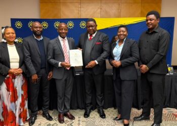WhatsApp Image 2026-08-10 at 35809 PM - The Brief | Namibia's Leading Business & Financial News Six professionals in business attire posing for a photo at a ceremony, with a man in the center holding a certificate.