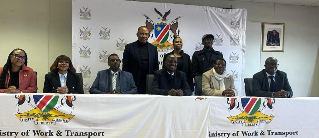 NAC - The Brief | Namibia's Leading Business & Financial News Group of seven officials seated at a long table with a Ministry of Work & Transport banner and crest behind them.