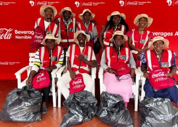 WhatsApp Image 2026-08-11 at 104904 AM - The Brief | Namibia's Leading Business & Financial News Group of Coca-Cola Namibia volunteers in red vests and hats pose for photo with trash bags at a Beverages Africa event backdrop