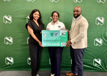 WhatsApp Image 2026-08-11 at 43049 PM - The Brief | Namibia's Leading Business & Financial News Three people pose with a large Nedbank Go Green debit card prop in front of a green backdrop featuring white logos, smiling for the photo.