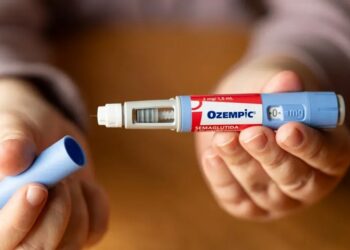 OZEMPIC - The Brief | Namibia's Leading Business & Financial News Close-up of a hand preparing an Ozempic diabetes injectable pen, with the blue cap removed and the needle exposed.