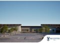 Exterior view of Buchter Mall with modern curved entrances, palm trees, and a clear blue sky; parking lot in foreground.