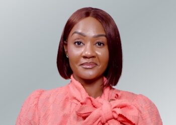 Sara Mezui Engo - The Brief | Namibia's Leading Business & Financial News Portrait of a woman with a burgundy bob, wearing a pink blouse with a bow, smiling at the camera.