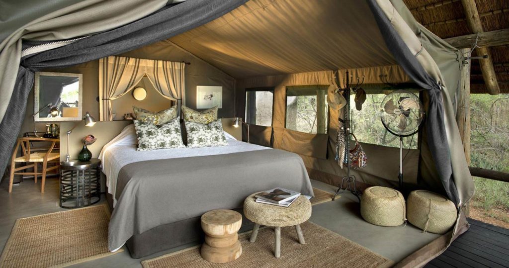 WhatsApp Image 2026-08-18 at 90129 AM - The Brief | Namibia's Leading Business & Financial News Luxurious safari-glamping bedroom in a canvas tent with a king bed, canopy, and decorative pillows. In-room seating and warm lighting create a cozy retreat at the camp.