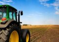 AGRICULTURE TRUCK - The Brief | Namibia's Leading Business & Financial News Green tractor with large yellow wheels on a flat farm field under a bright blue sky