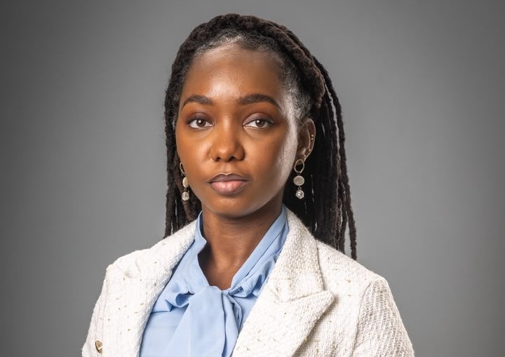 Tunohole Mungoba - The Brief | Namibia's Leading Business & Financial News Professional headshot of a Black woman with braided hair, wearing a light blazer and pale blue blouse, against a gray studio backdrop.