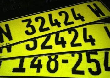 Bright yellow license plates with large black numbers stacked diagonally in the frame, overlapping each other.