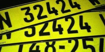 Bright yellow license plates with large black numbers stacked diagonally in the frame, overlapping each other.