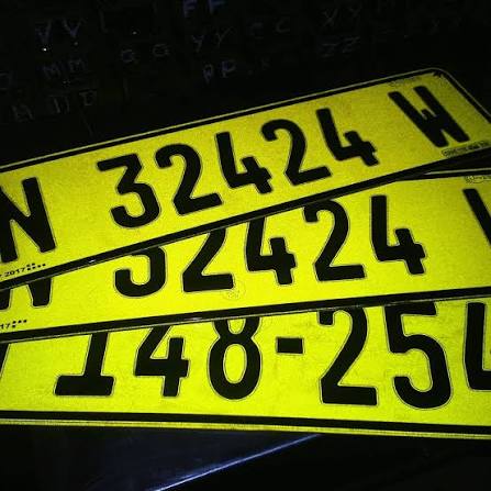 Bright yellow license plates with large black numbers stacked diagonally in the frame, overlapping each other.